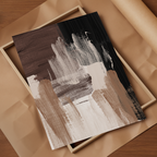 Abstract canvas art print featuring textured brushstrokes in black, brown, beige, and white, styled on a wooden surface.