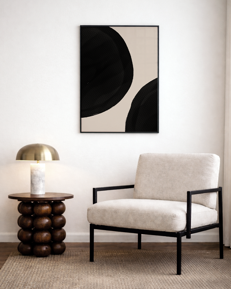 Modern living room with a beige armchair, side table, and abstract art on the wall.