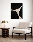 Modern living room with a beige armchair, side table, and abstract art on the wall.