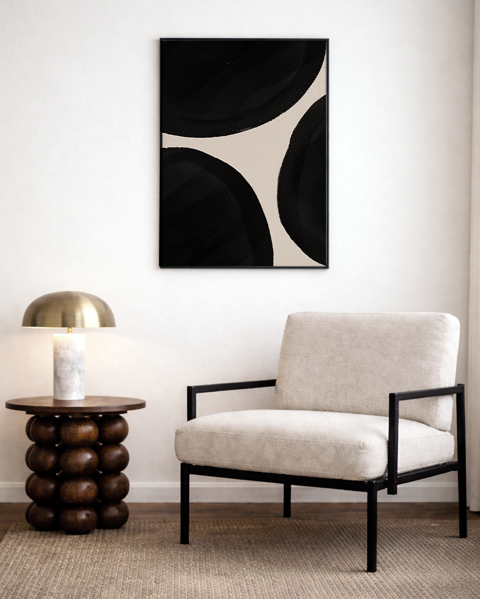 Modern living room with a beige armchair, side table, and abstract art on the wall.