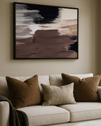 Beige sofa with brown and beige pillows in a living room setting, featuring an abstract bold and brown canvas on the wall.