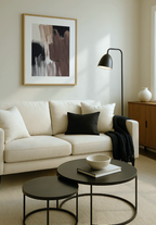 Modern neutral living room with a white sofa, black coffee table, and abstract brown art on the wall.