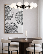 Dining room with a round wooden table, four chairs, a wall art piece, and a chandelier.