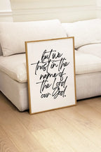 but we trust in the name of the Lord wall art in front of the sofa