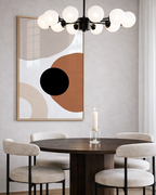 Dining room with a round table, chairs, abstract burnt orange wall art, and modern chandelier.