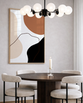 Dining room with a round table, chairs, abstract burnt orange earthy wall art, and modern chandelier.