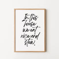 Framed typographic wall art with black handwritten text reading 'In this house we eat rice and stew.' 