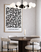 Dining room with a leopard print poster on the wall, round wooden table, and chairs.