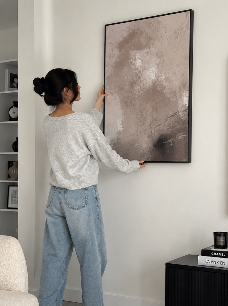 Person hanging a large abstract painting on a wall