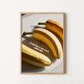 A framed art print featuring a stylized illustration of three bananas on a light gray background with the text 'PLANTAIN IS MY LOVE LANGUAGE'. 