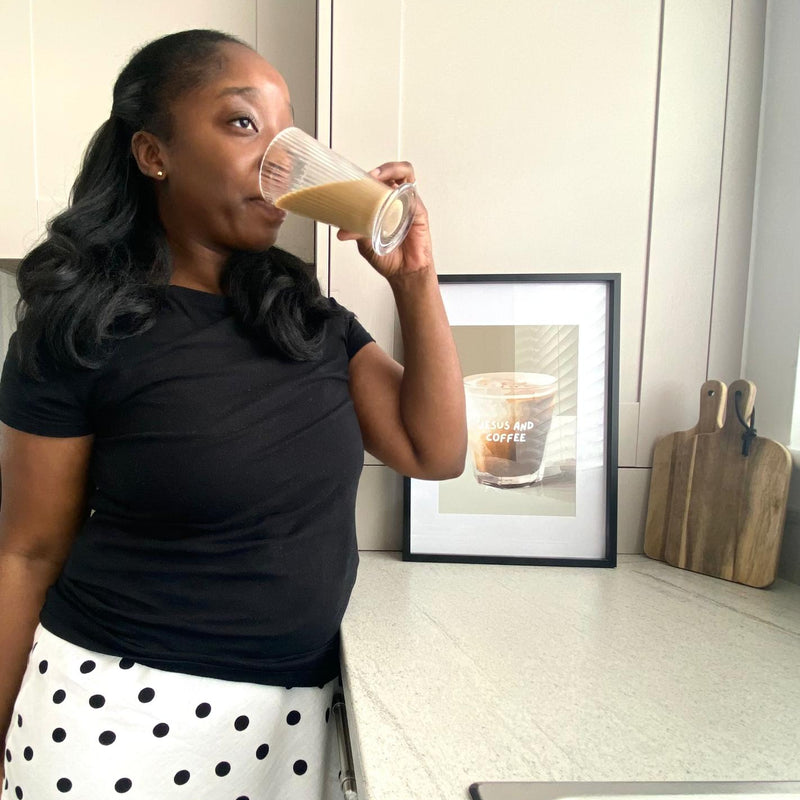 Woman drinking a coffee in a kitchen with art in the background