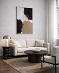 Modern living room with a beige sofa, abstract brown, black and beige wall art, and decorative items.